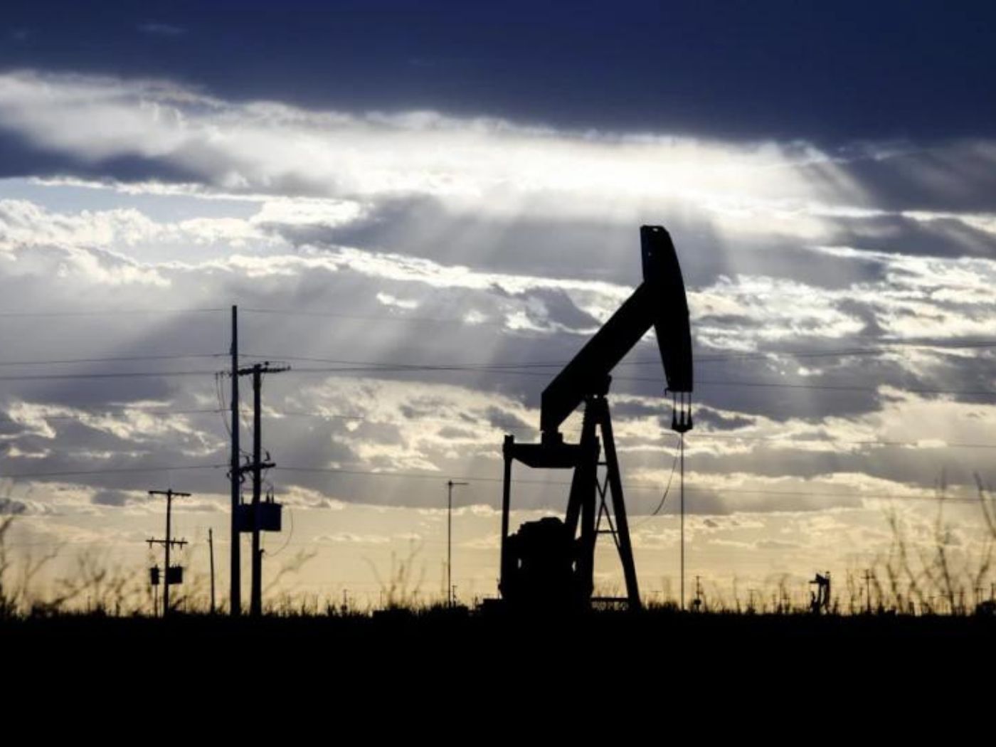  The sun shines through the clouds as it begins to set behind a pumpjack, March 30, 2022, outside of Goldsmith, Texas. 