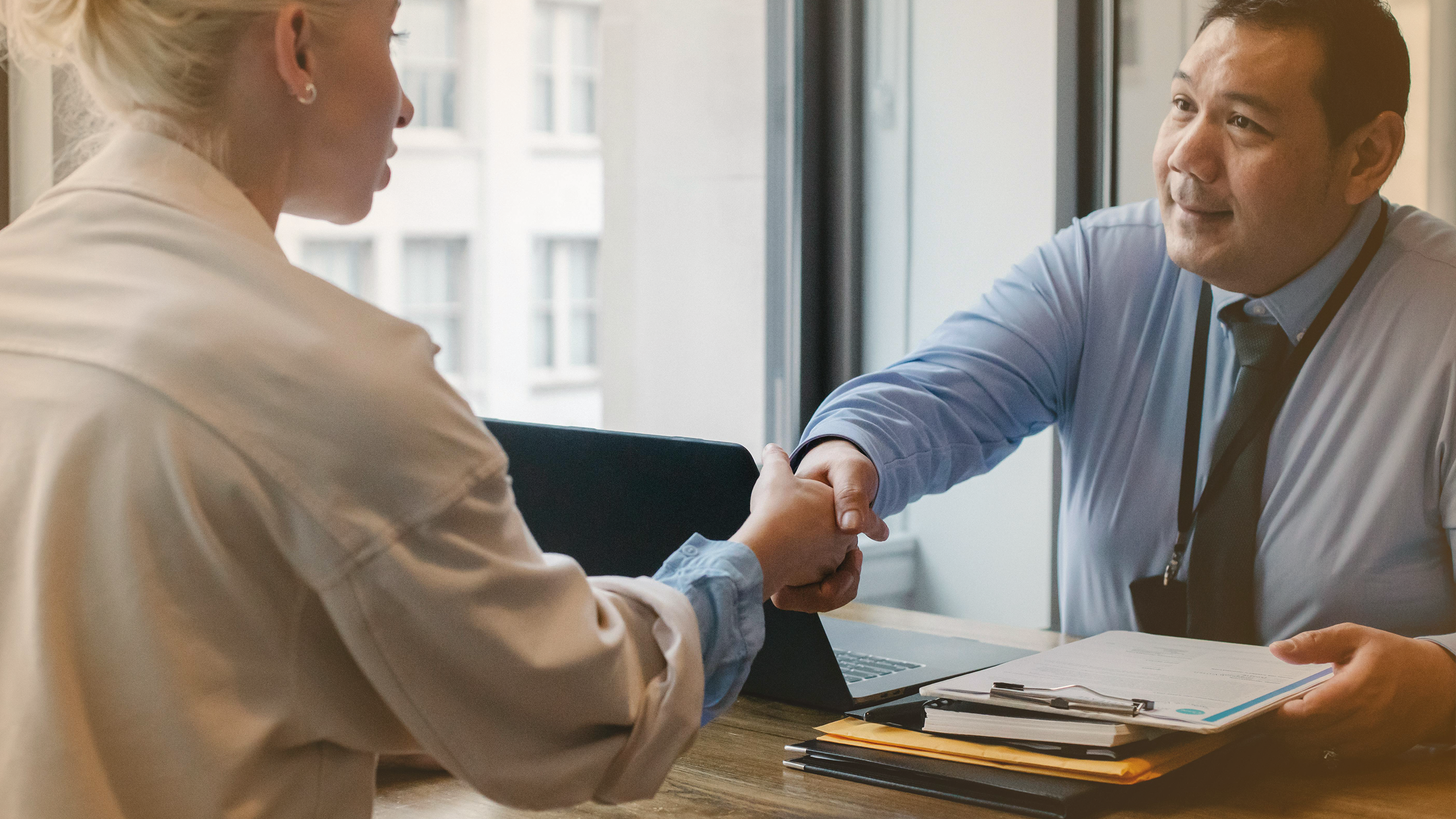 Financial advisor shaking hands with a client, relating to financial advice for consumers and households