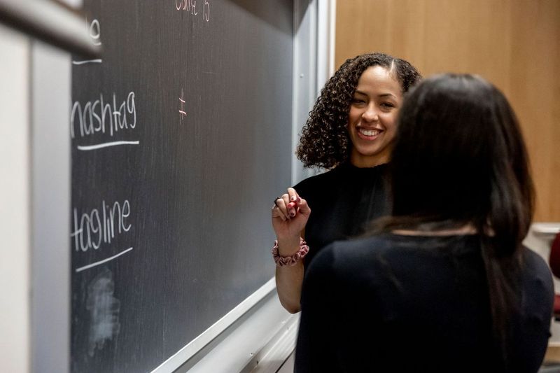 Two undergraduate students stand at a chalkboard and work together