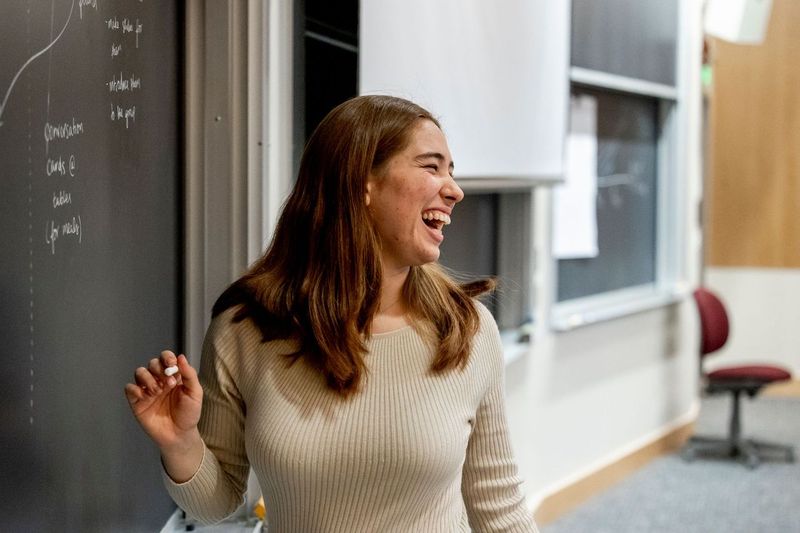 An MIT Sloan students stands at a chalkboard. 