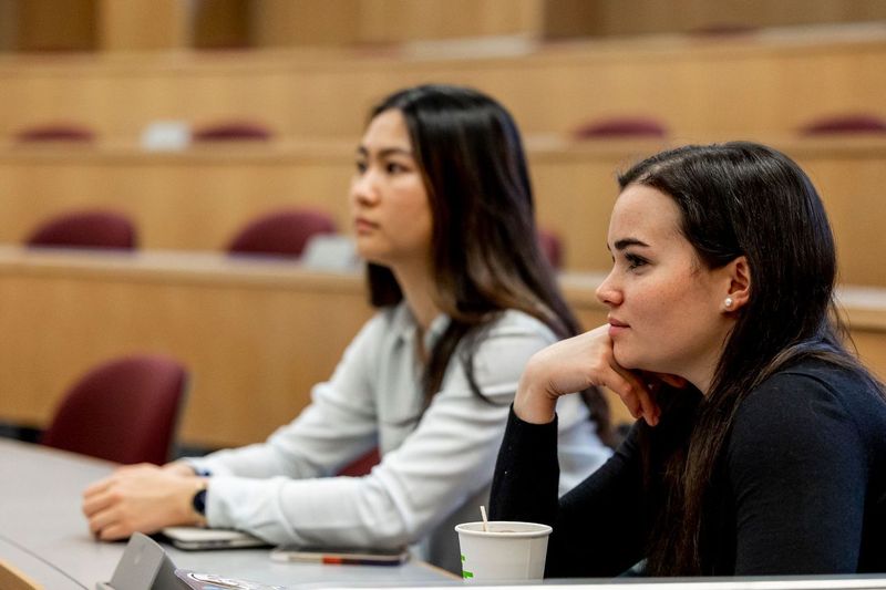 Two MIT Sloan students sit in a lecture hall.
