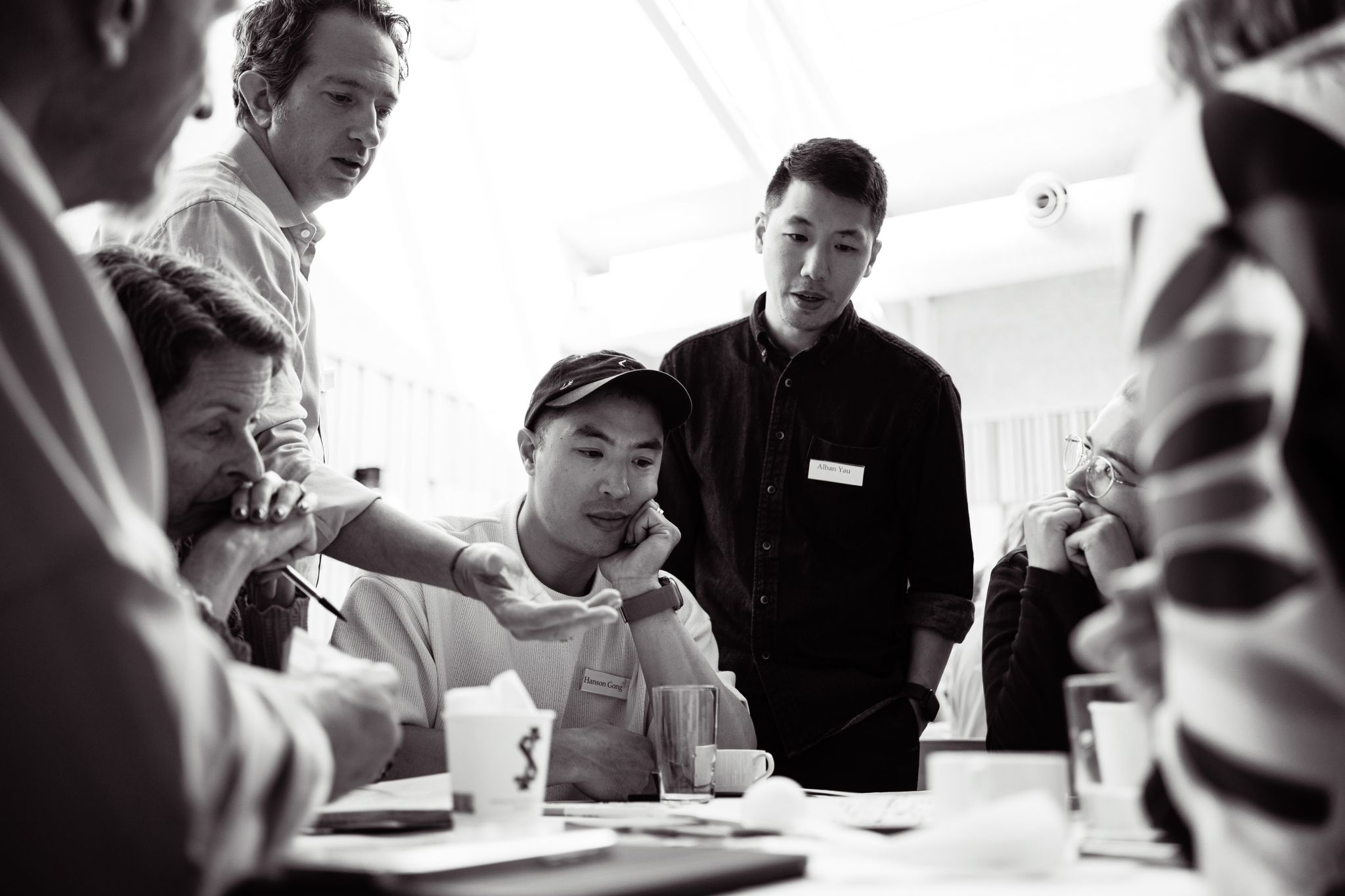 Black and white photo of Jason and Alban Yau with participants in the Investing for Systems Change program