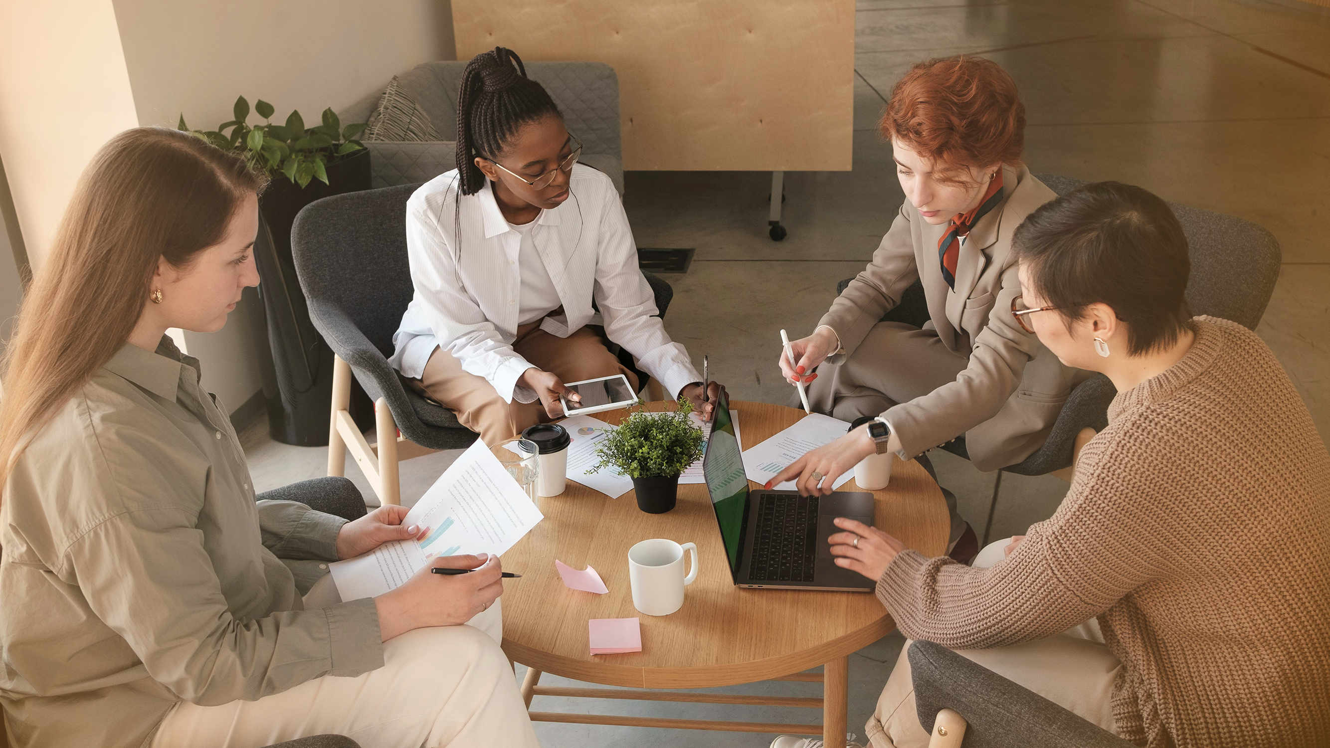 Group of women around table discussing bankruptcy and reviewing banking documents