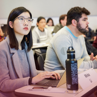 Students in the Masters of Finance program listen to a lecture in a classroom