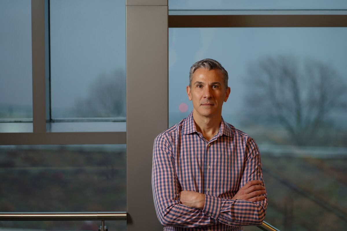 MIT Sloan Professor Emilio J. Castilla standing in front of windows in the MIT Sloan building, with wintry trees in the  background outside