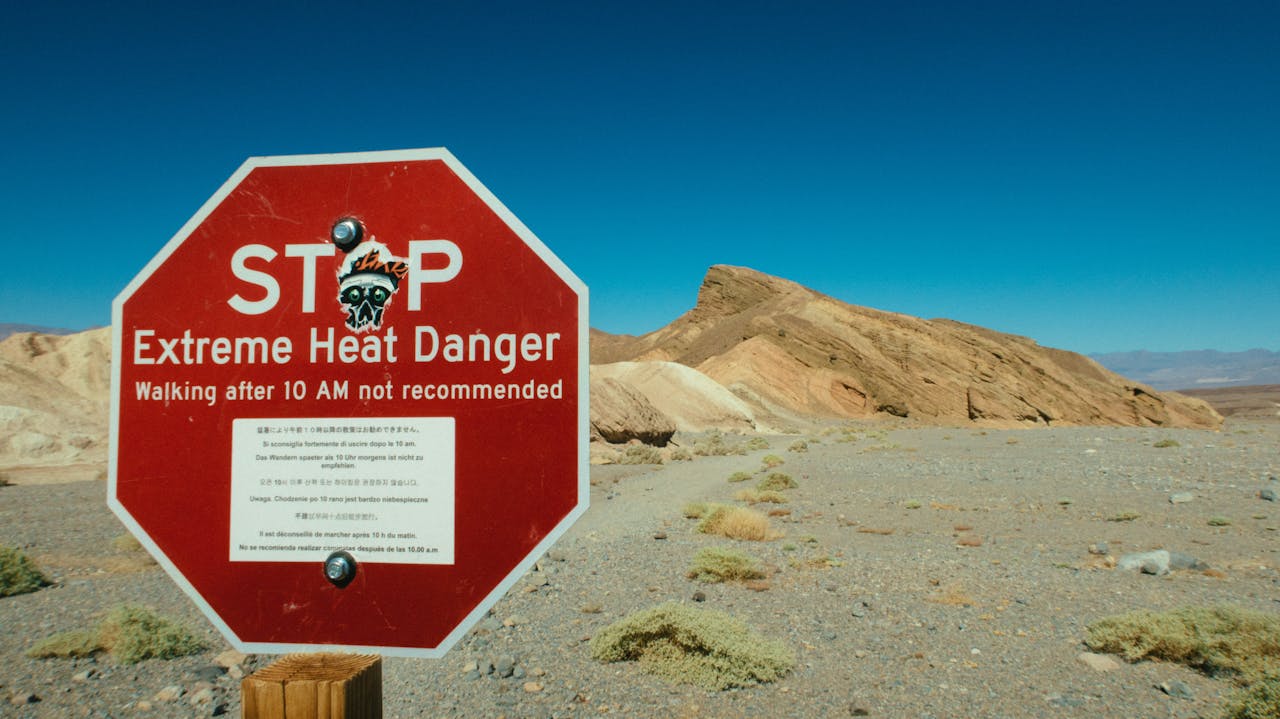 A stop sign that says "STOP Extreme Heat Danger" in a desert-like area