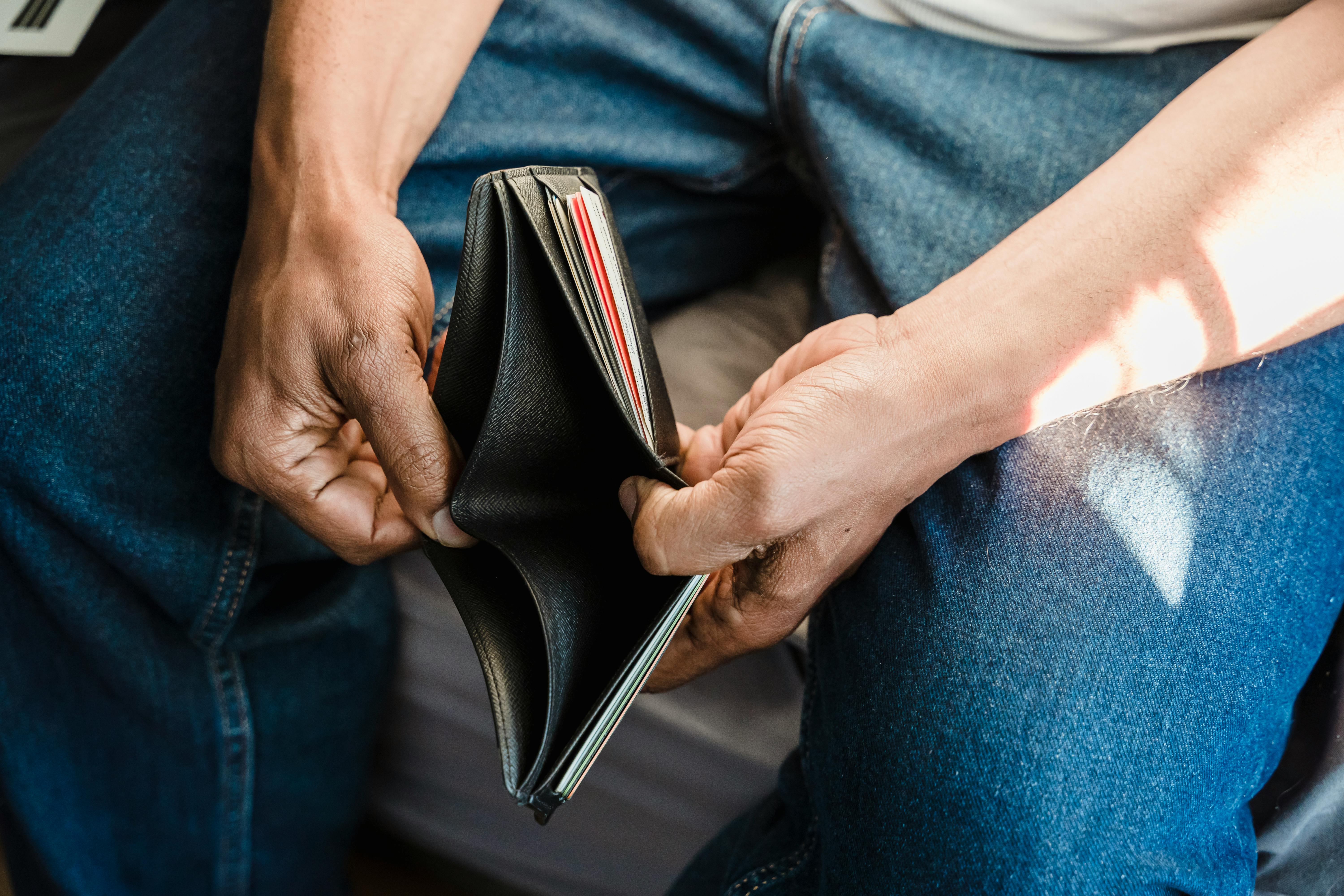 Image of a man's hands opening a wallet that contains no cash