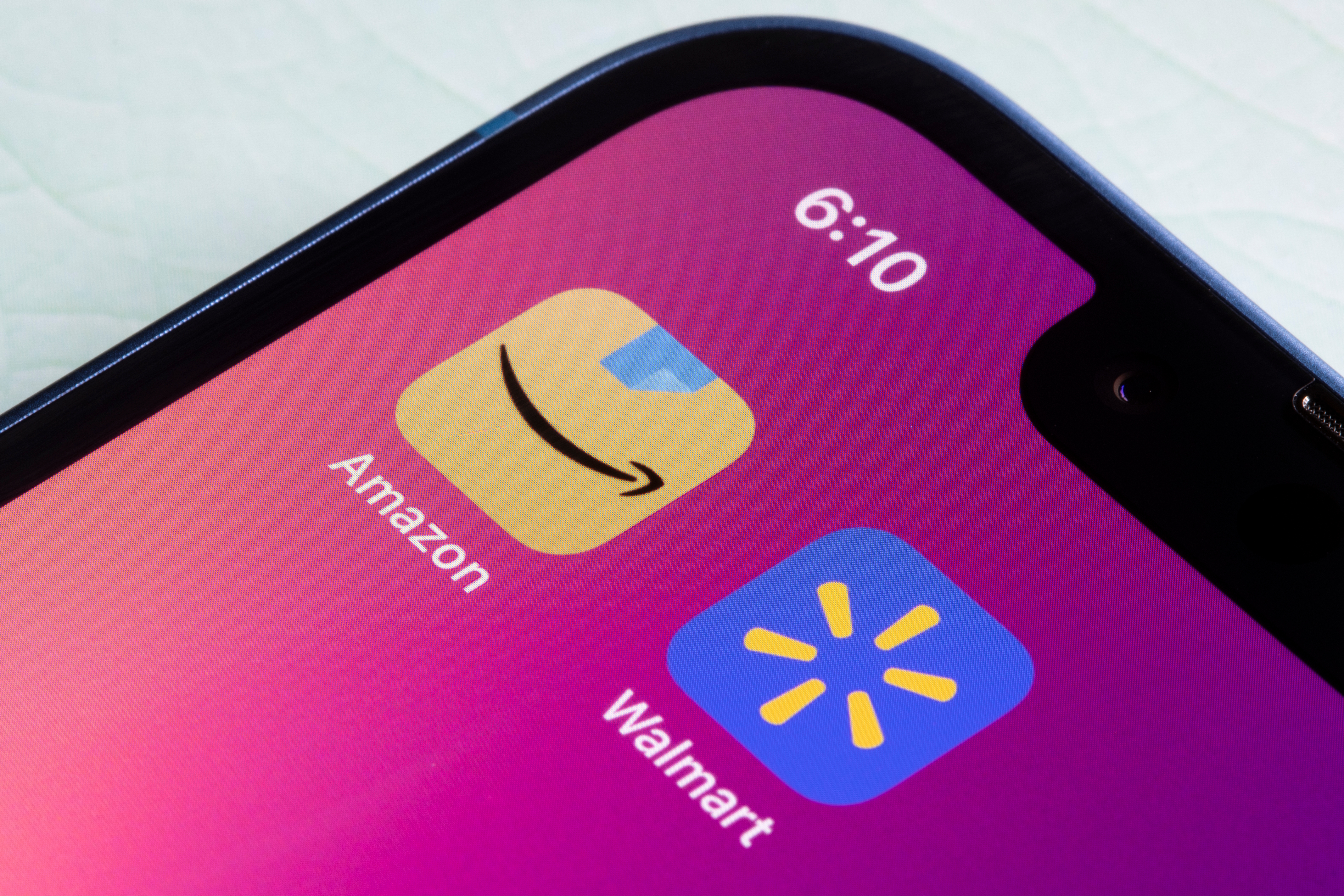 Phone showing Amazon and Walmart apps on purple background