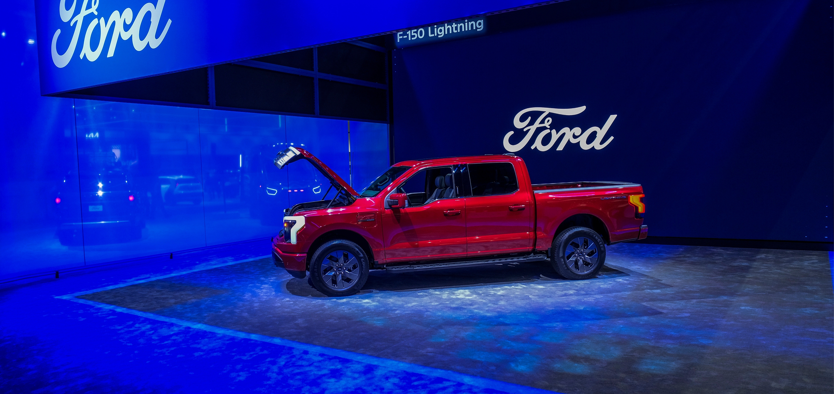 Red ford truck with open hood in a car show environment