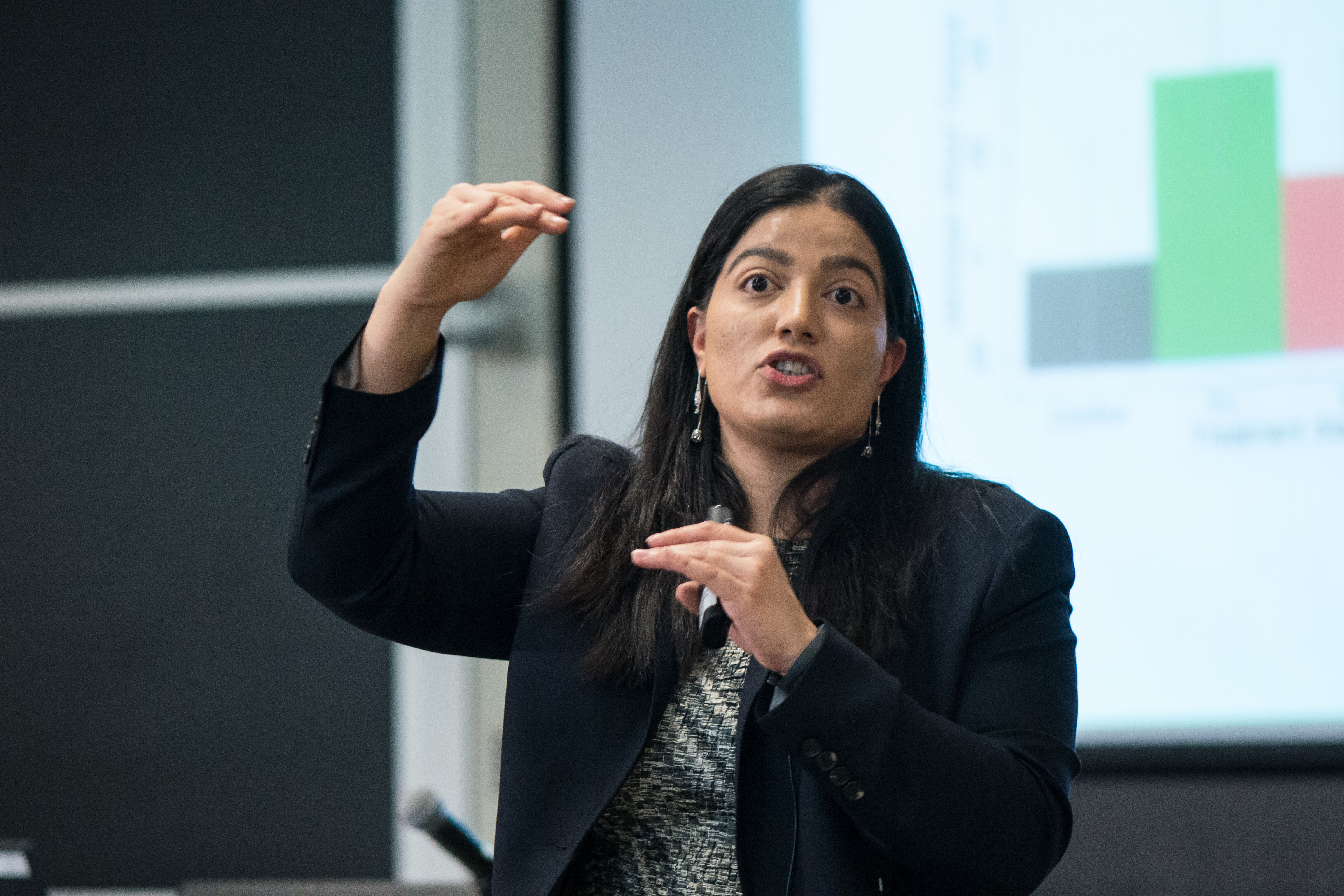 Professor Tavneet Suri teaching a class in front of a bar graph