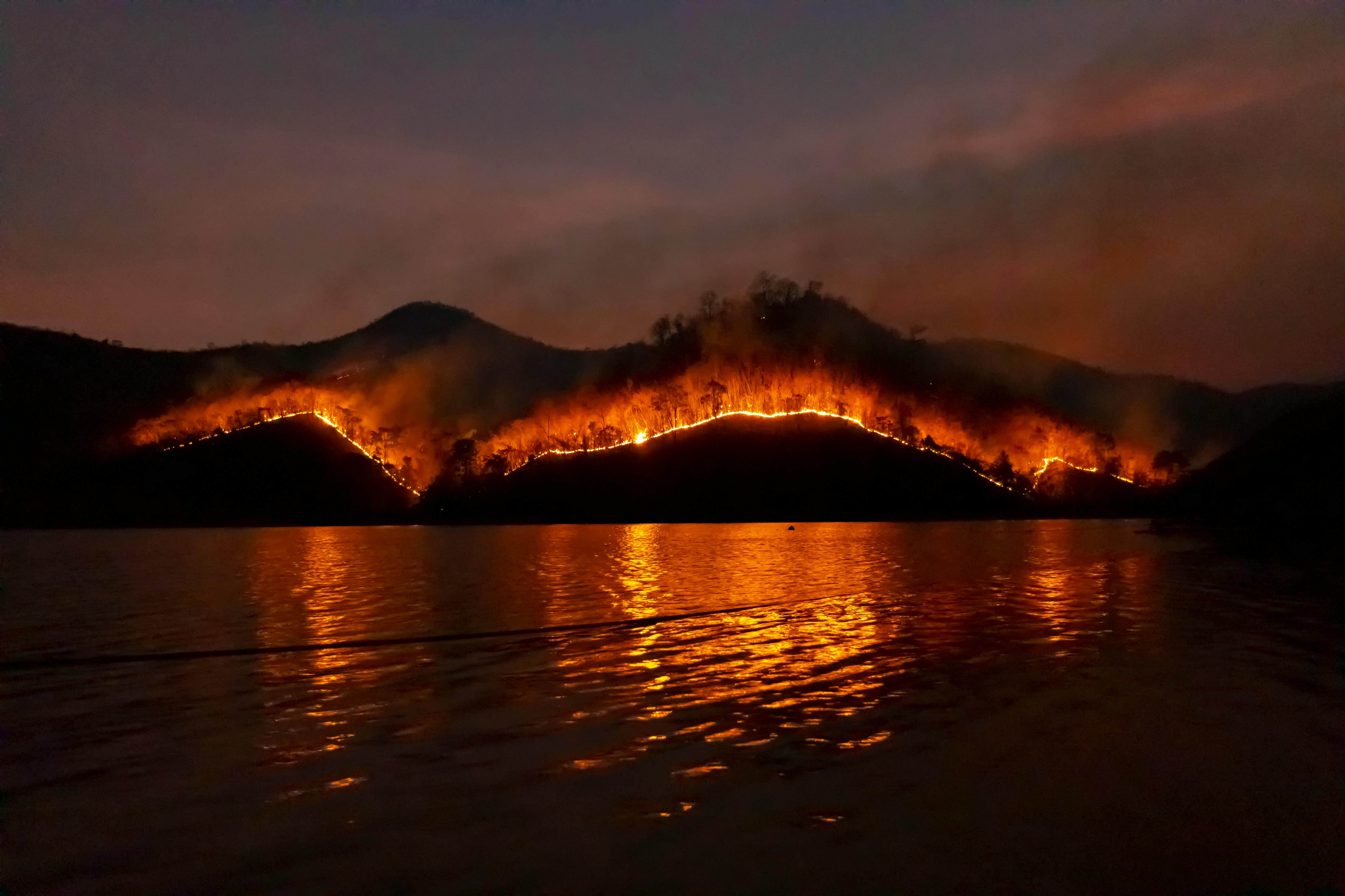 wildfires burning behind a body of water at night
