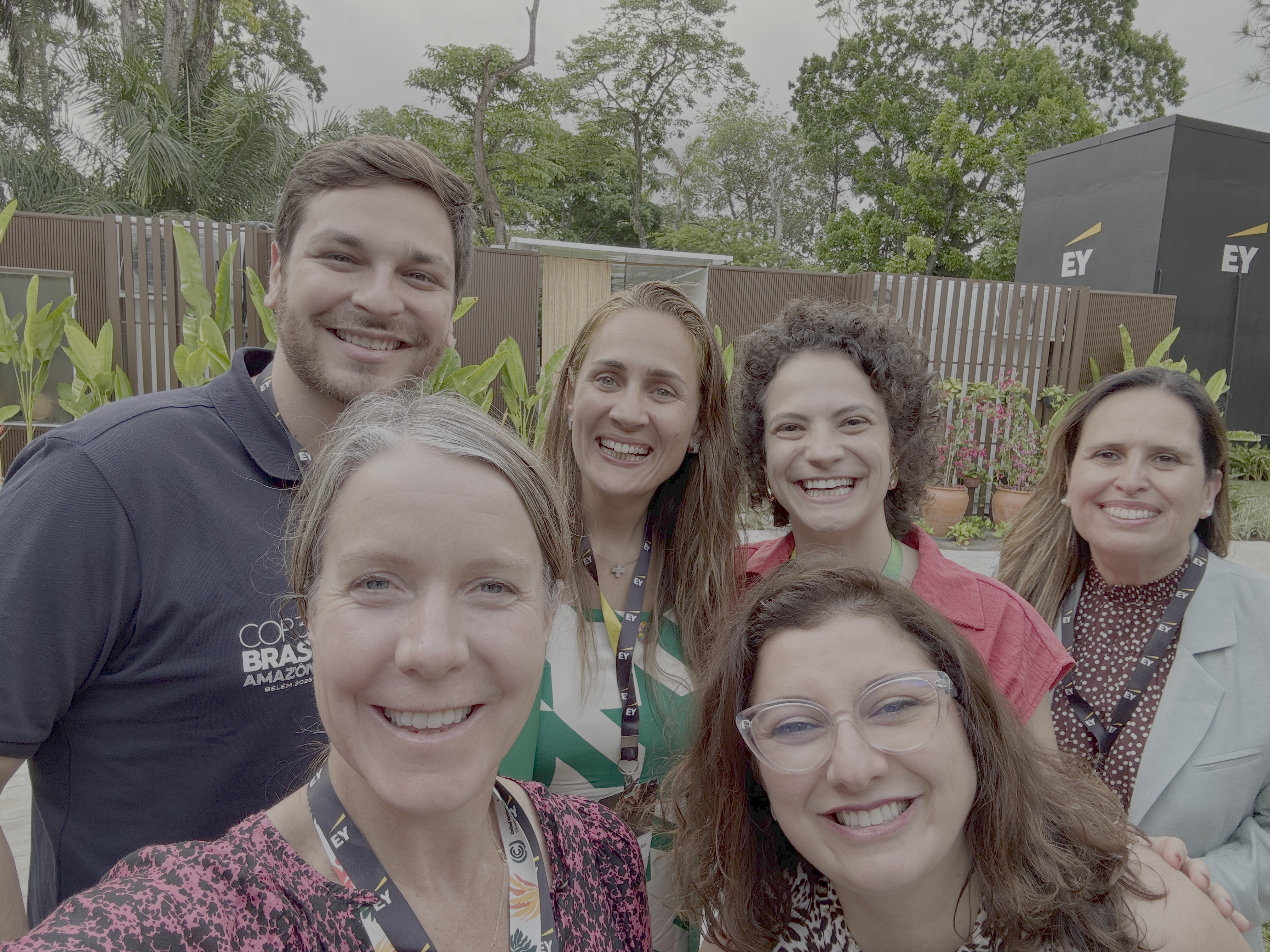 2 people smiling and 4 people smiling behind them posing for a selfie. 