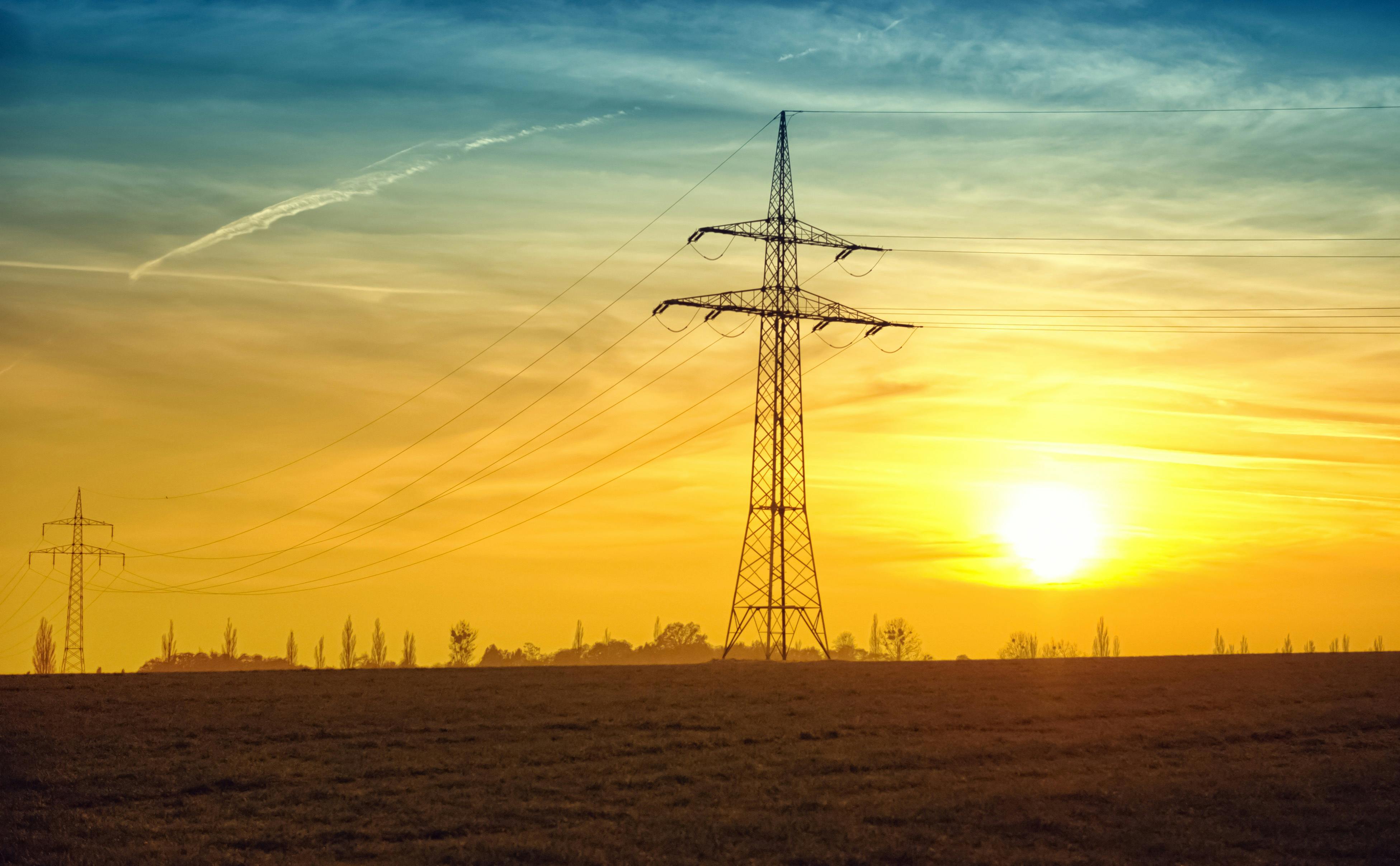 Power lines across a sunset sky and barren land
