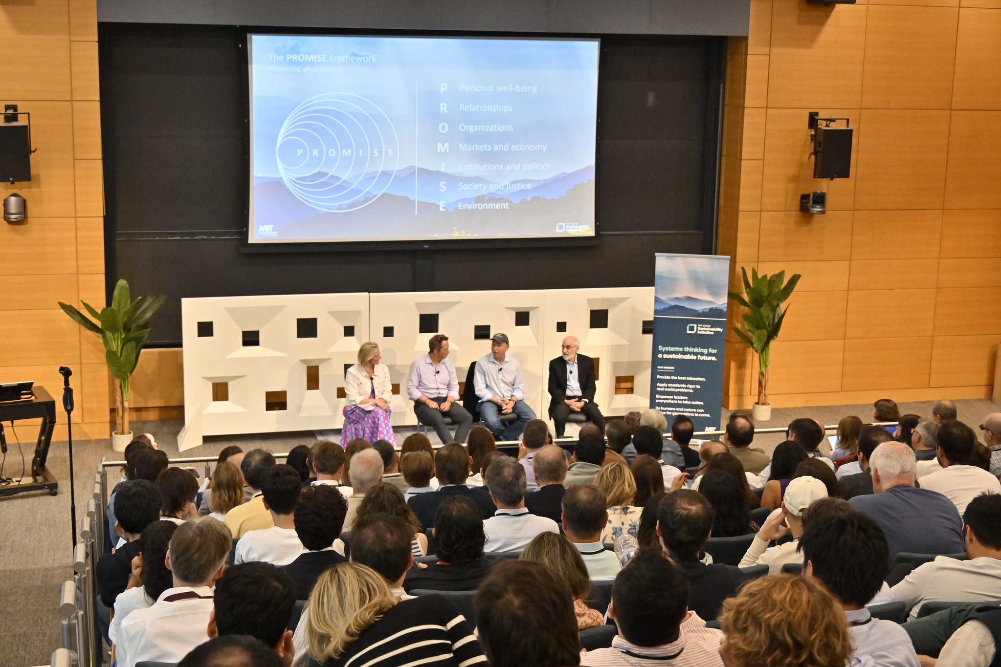 A panel presents to a crowded auditorium.