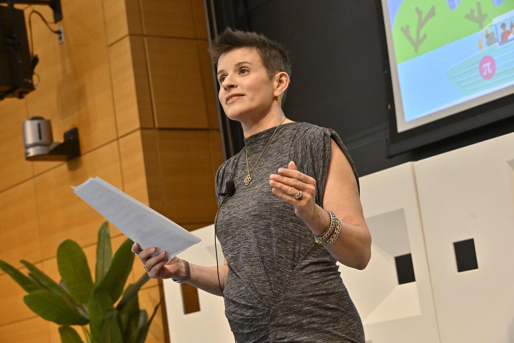 A woman reads from a paper while presenting.