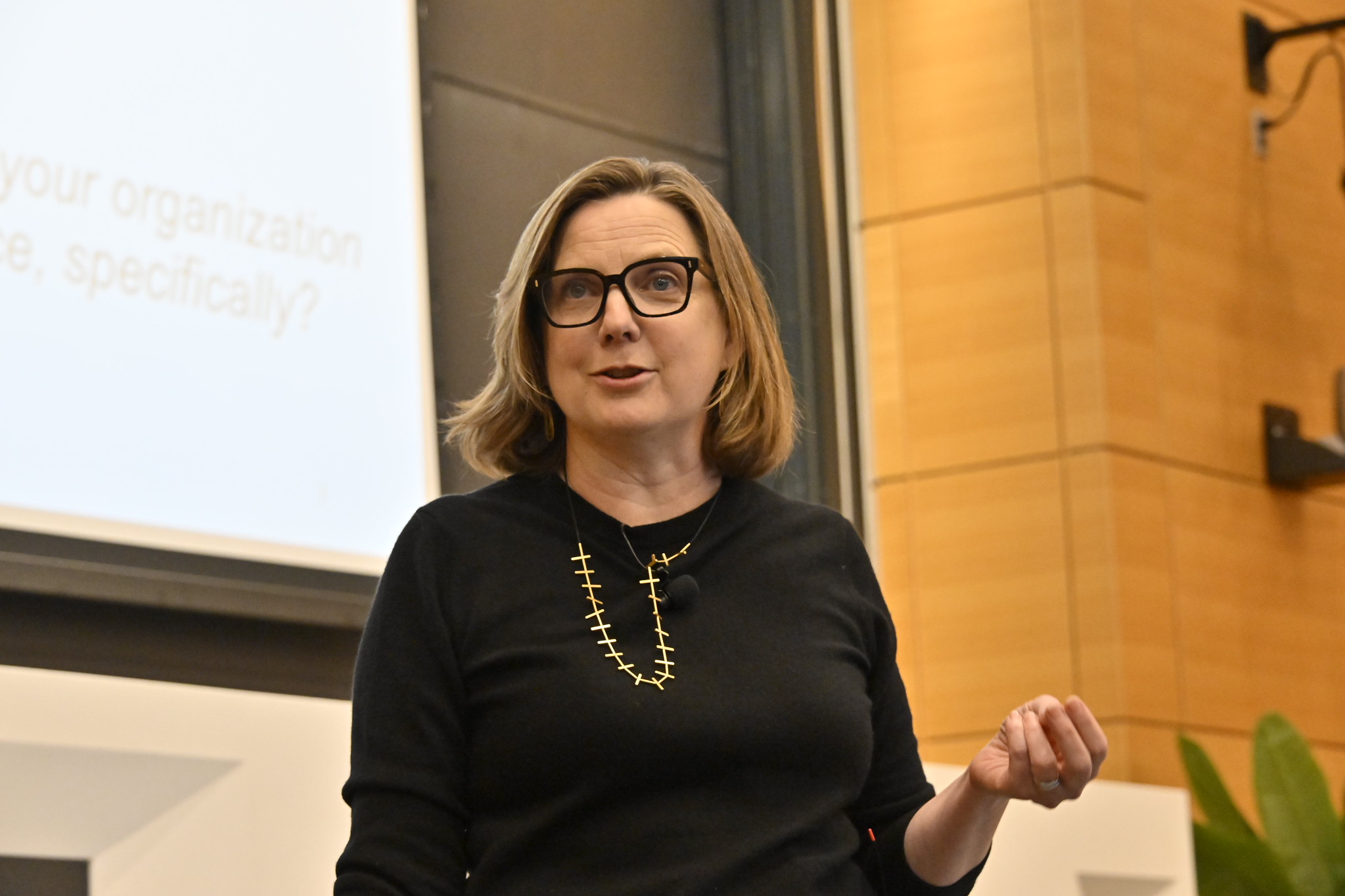 Woman in glasses gestures during presentation.