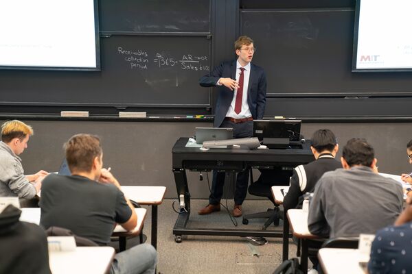 Faculty member lectures to students at the front of a classroom