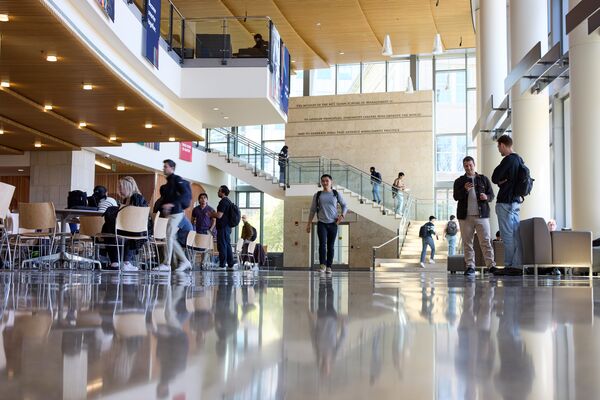 Students walk and converse between classes in a school lobby