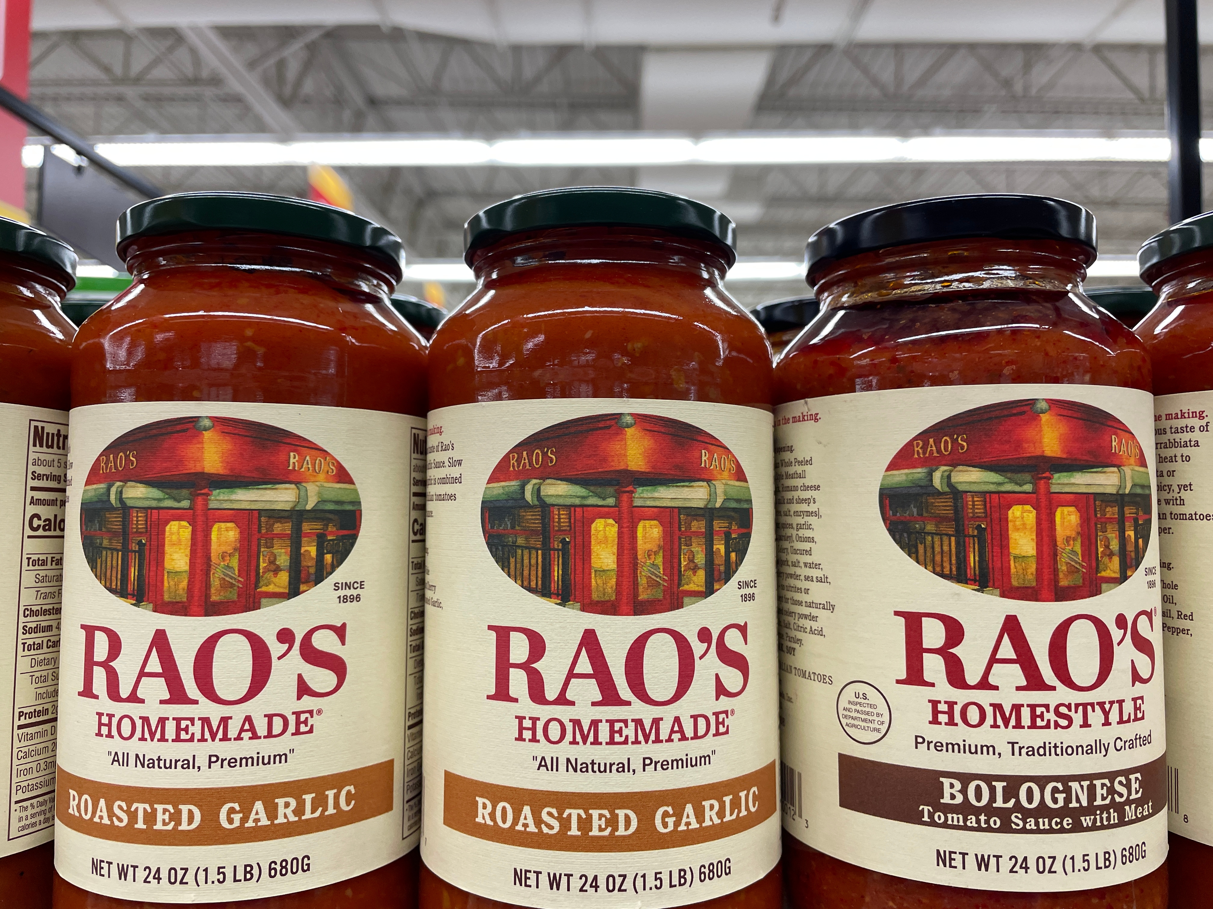 Three jars of Rao's tomato sauce up close with warehouse ceiling in background