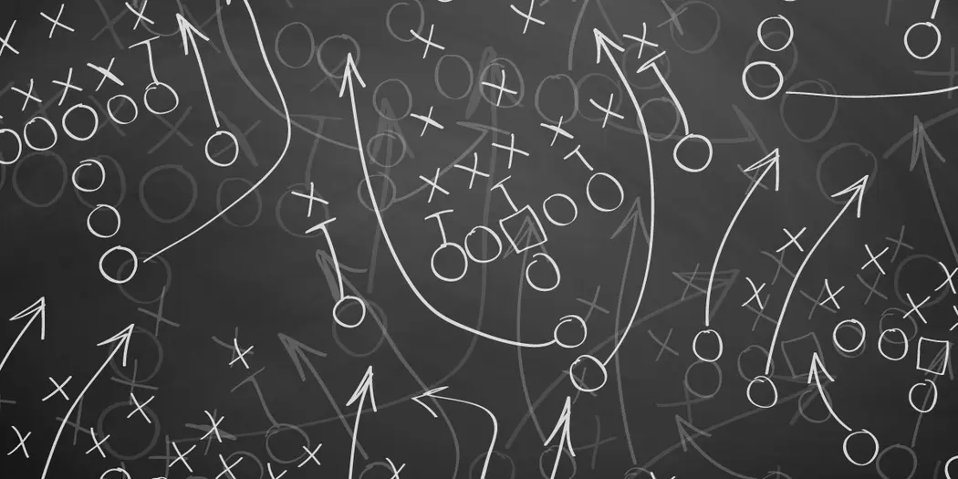 An image of a blackboard with a football-like play drawn up, representing strategy.
