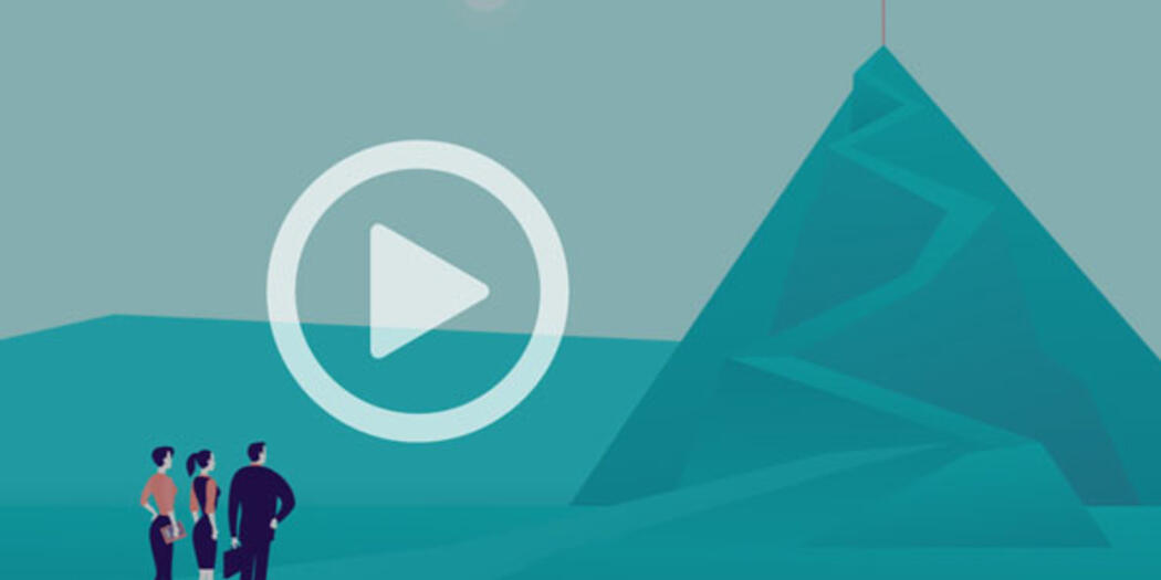 A group of people looking toward a red flag on top of a mountain.