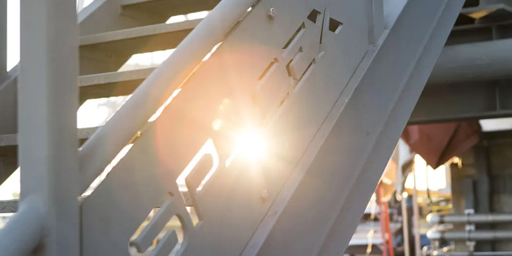 A railing with the sun shining through the SpaceX logo 