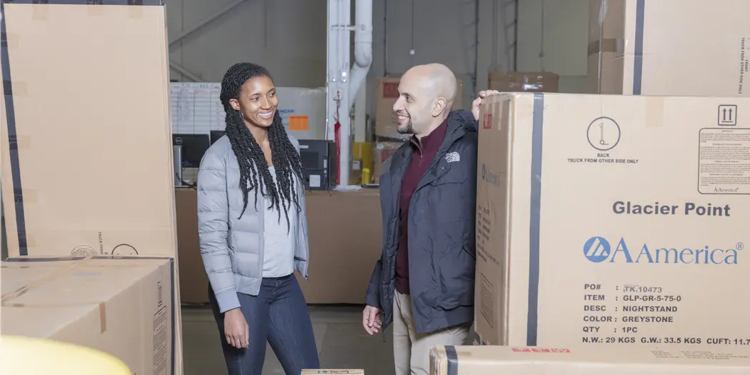 Ops-Lab student and host among boxes in Wayfair warehouse