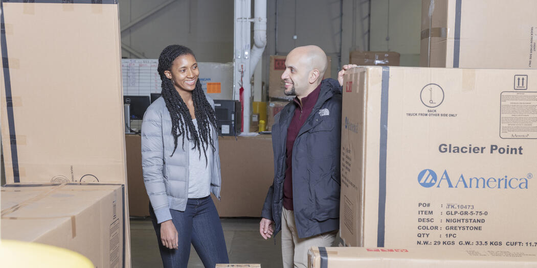 Ops-Lab student and host among boxes in Wayfair warehouse