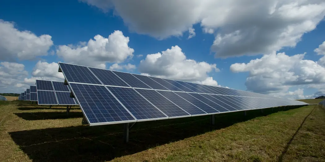 Solar panels in a field on a partly cloudy day