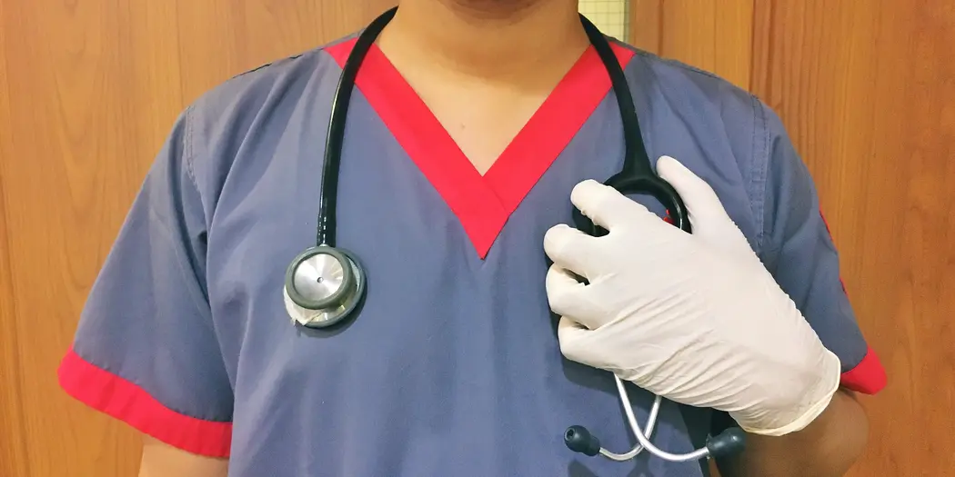 Nurse in face shield and mask with stethoscope draped over her shoulders