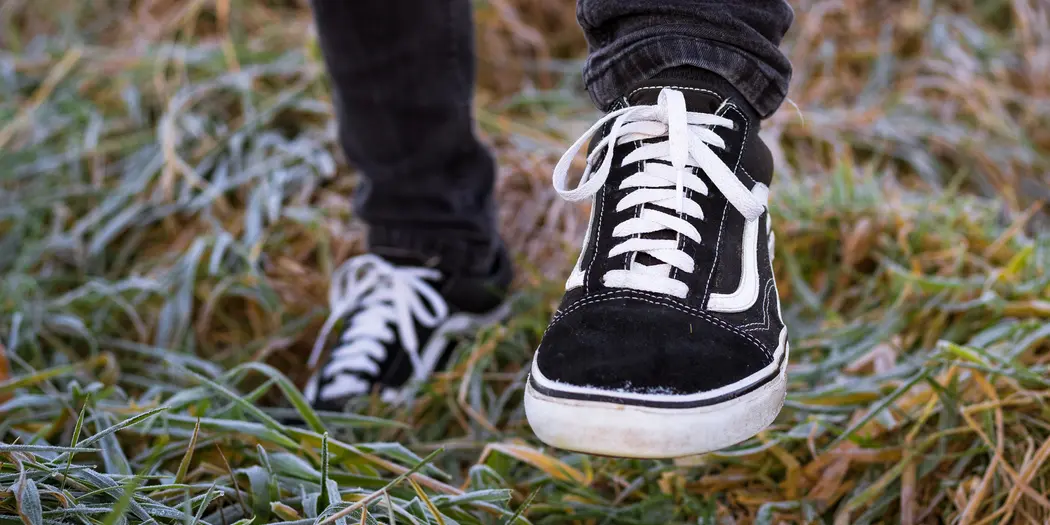 Close up of black sneakers on feet, standing on grass