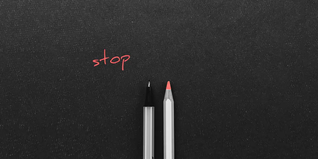 A pen and a colored pencil side by side with the word "stop" above