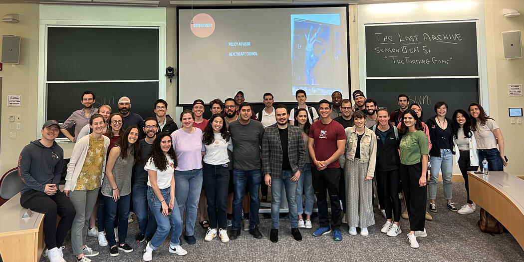 Group of students poses in front of a chalkboard in a classroom