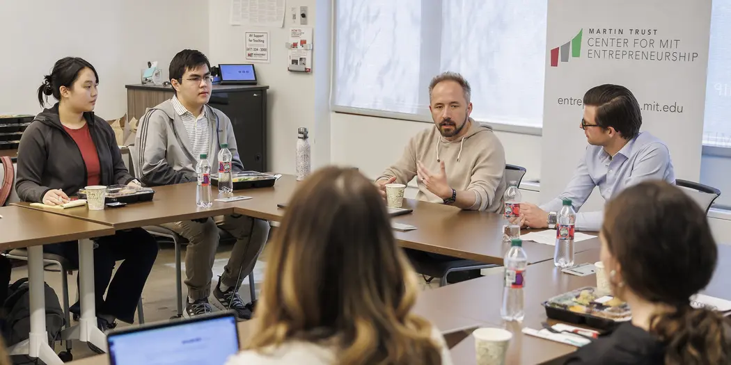 A man speaks to students at a table