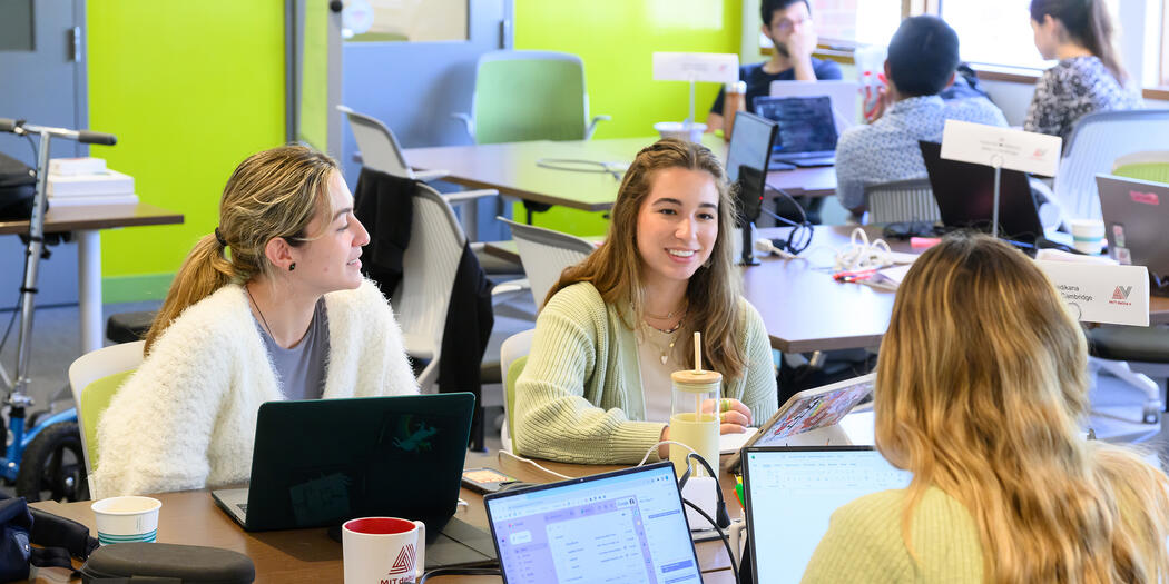 Students sit together in groups discussing their projects