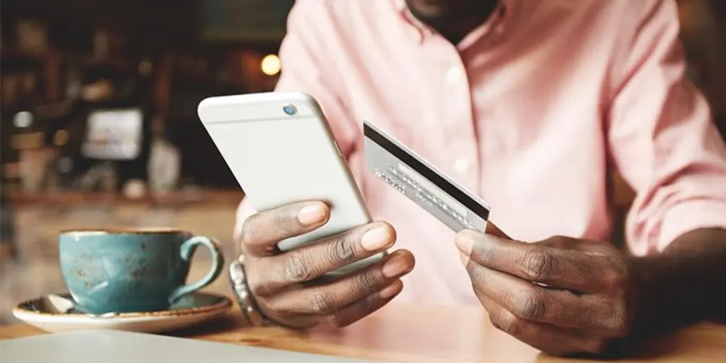 Photo of man holding up credit card to smart phone