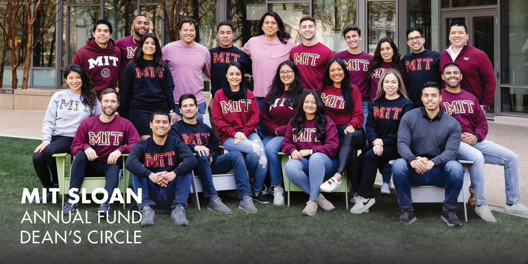 A group of students wearing MIT sweatshirts pose for a photo outside of Building E62