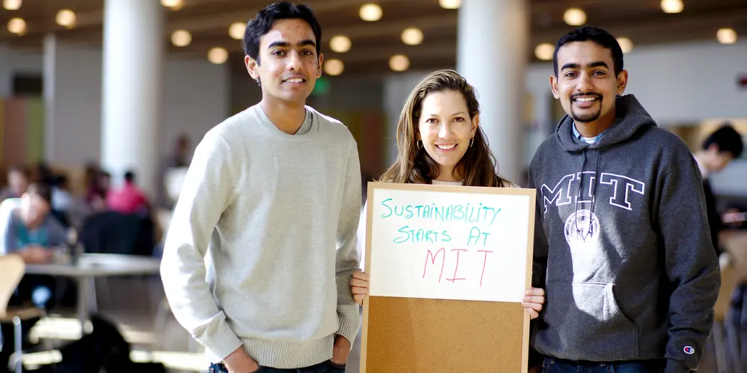 Three people holding a sign that says "Sustainability Starts at MIT"