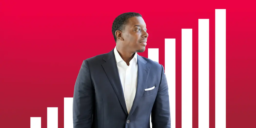 A man in a suit looks off camera to his left on a background of red with white stripes