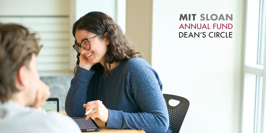A student smiles while working at a desk