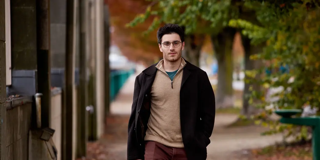 PhD student Ben Manning walks towards the camera. It's a fall day. 
