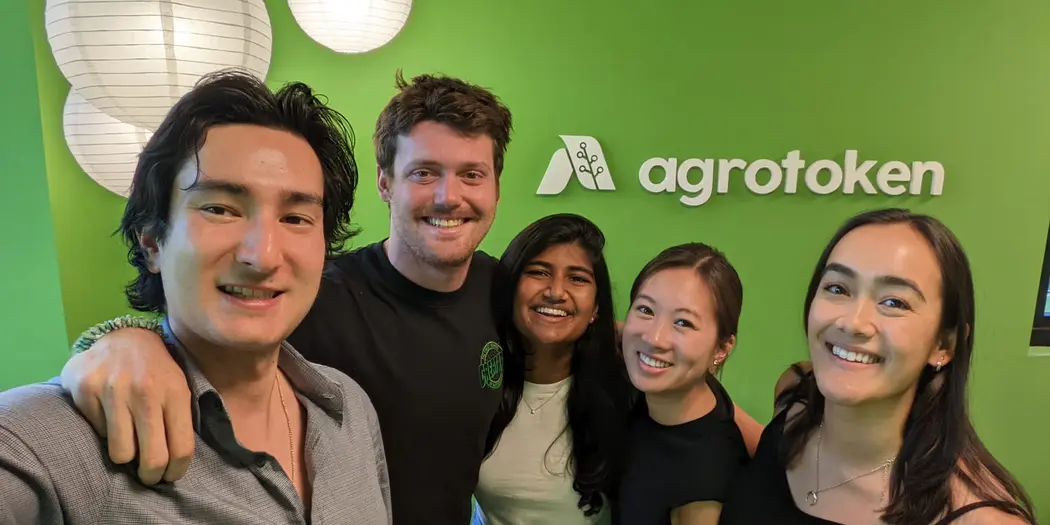 G-Lab students and host standing in front of green wall with agrotoken's name and logo on it