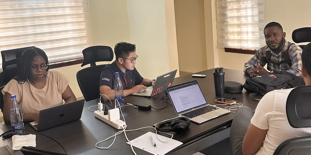 Students and host sitting at a conference room table with their laptops open