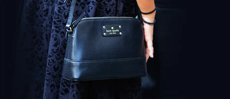 Person carrying a black Kate Spade bag