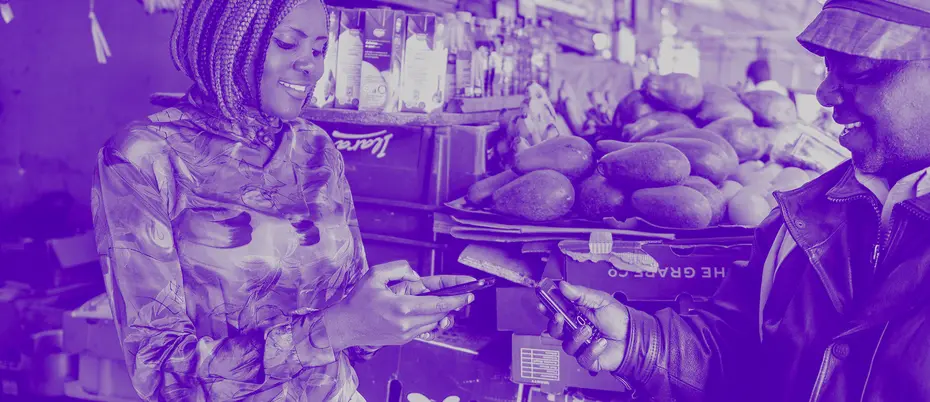Man using mobile money to buy from a woman in a market
