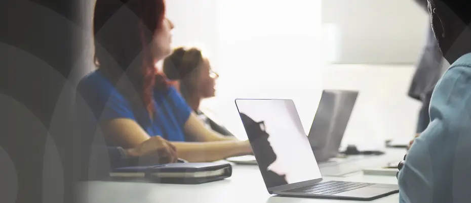 People in a classroom setting, sitting by computers