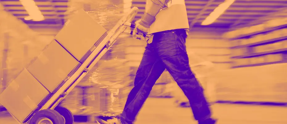 Worker wheeling stack of boxes 