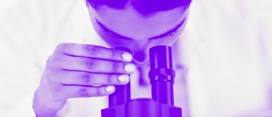 Scientist looks through a microscope