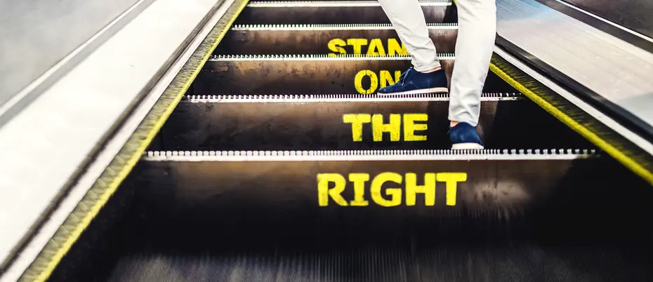 Man standing on right side of the escalator over words "Stand on the right"