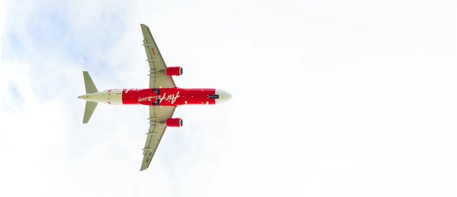 red and white air asia plane flies through a blue sky